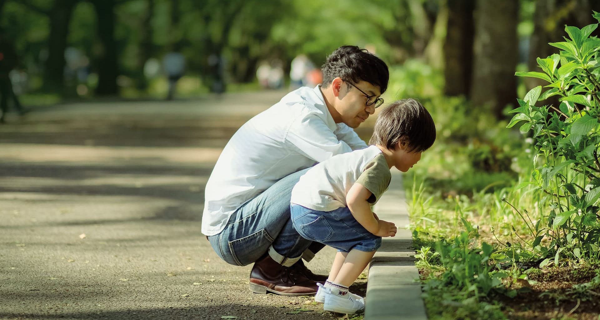 Father and son looking at plants in a park